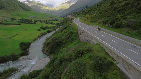 Cyclists-on-a-road-in-Swiss-Alps-with-cars-and-rainbow-at-the-sky-shot-from-a-drone