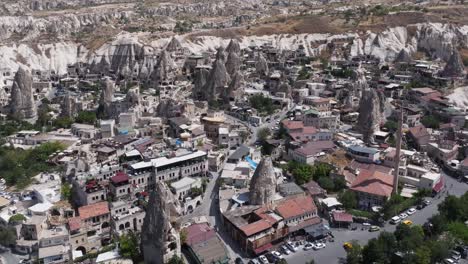 Drone-descends-over-rock-spires-with-homes-built-along-roads-in-valleys-on-edge-of-Cappadocia-Turkey