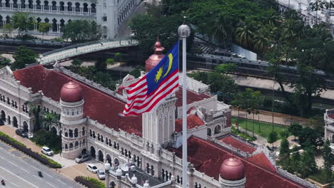 Drone-orbiting-the-Malaysian-flag-in-downtown-Kuala-Lumpur,-sunny-day-in-Malaysia