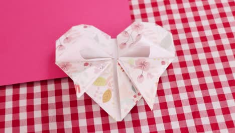 Folded-heart-from-decorative-origami-paper-on-checkered-tablecloth