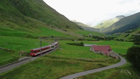 Train-going-through-the-scenic-Swiss-Alps-during-summer-at-Furka-Pass,-shot-from-a-drone-in-4K