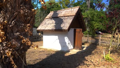 Small-Thatched-Roof-Cottage-with-a-Wooden-Door-in-a-Quiet,-Rural-Countryside-Setting