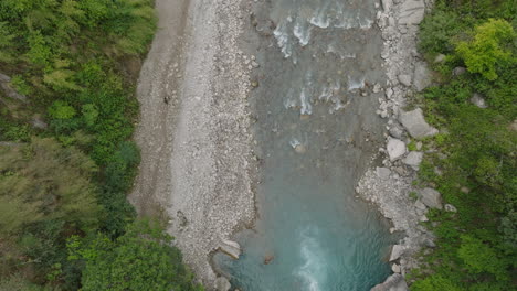 Bird's-eye-view-captures-a-trekker-hike-witnessing-landscape-of-Langtang-National-Park,-Nepal,-river-flows-silently-through-lush-greenery-along-peaceful-riverbanks,-creating-atmosphere-in-nature