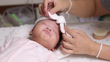 A-mom-is-putting-on-a-white-headband-on-her-newborn-child's-head-while-it-is-sleeping