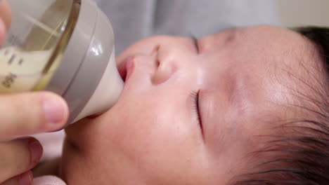 A-sleeping-newborn-child-is-latching-on-to-a-baby-feeding-bottle-while-it-drowses-off-to-sleep