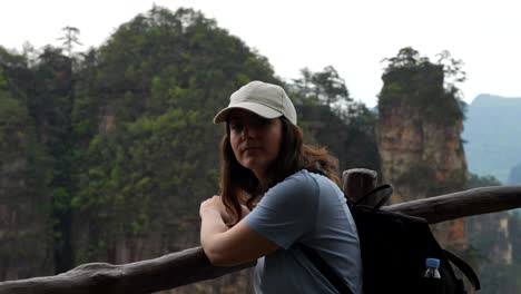 Woman-smiling-at-camera-turns-to-admire-scenery-of-Huangshi-Village-from-viewpoint,-China