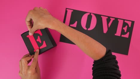 Gluing-pink-letters-on-black-paper-to-form-word-LOVE-in-A-team-font