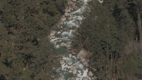 Aerial-view-of-river-flowing-from-Himalayas-through-Langtang-National-Park,-Nepal-river-rushes-past-huge-forests-and-boulders,-offering-thrilling-adventure-in-the-wildness-for-tourism-in-Nepal