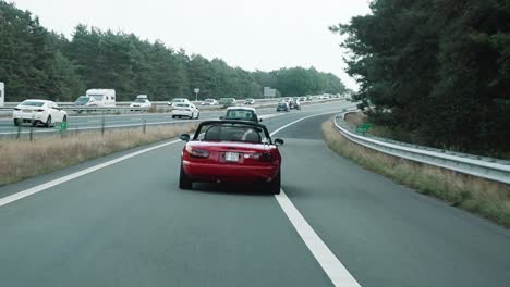 Red-old-timer-car-driving-fast-on-to-the-highway-of-Belgium-to-The-Netherlands