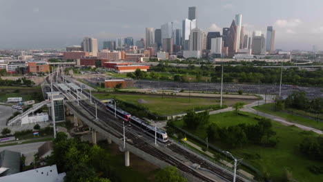 Drone-following-the-Metro-moving-toward-the-downtown-of-Houston,-golden-hour