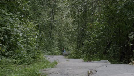 A-lone-hiker-walks-down-a-quiet-forest-trail-surrounded-by-lush-greenery