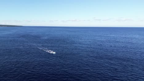 A-boat-travels-across-the-calm-blue-ocean-under-a-clear-sky