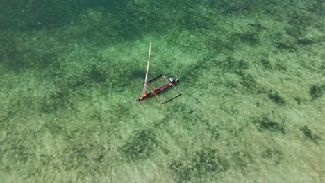 Sailboat-glides-over-clear-turquoise-water,-viewed-from-above