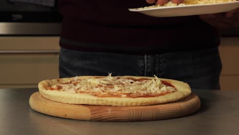 Man-adding-grated-cheese-to-a-homemade-pizza,-highlighting-the-preparation-process