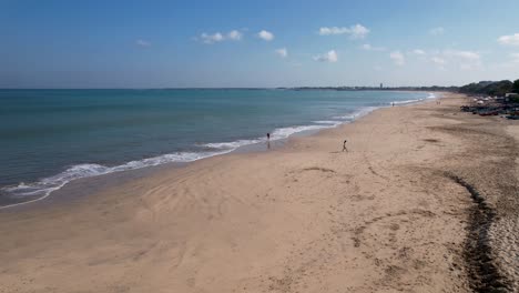 Aerial-video-on-Jimbaran-beach-at-Bali,-Denpasar,-Indonesia-during-a-sunny-day-with-calming-sea-waves.