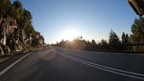 Group-of-adventure-bikers-riding-on-asphalt-road-near-the-sea-at-sunset