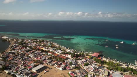 Colorful-seaside-town-and-turquoise-waters-in-los-roques-under-a-sunny-sky,-aerial-view