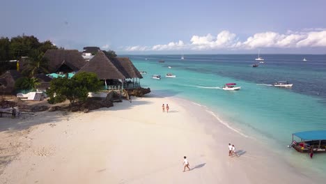 White-sand-beach-and-typical-boats-going-out-to-sea,-Zanzibar-on-sunny-day