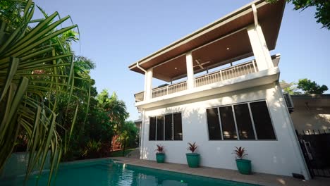 Exterior-view-of-an-elevated-house-with-a-pool-and-modern-design,-overlooking-the-surrounding-tropical-landscape,-pullback-of-exterior-of-home-house-for-real-estate-property