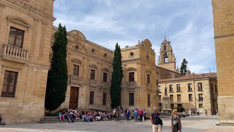 In-the-afternoon-filming-of-the-main-façade-of-the-Episcopal-Palace-located-on-the-west-side-of-the-cathedral-with-its-2-green-and-tall-cypresses-and-a-large-group-of-tourists-sitting-on-its-steps