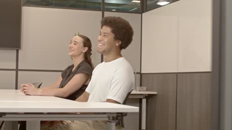 African-American-male-in-his-20's-and-a-caucasian-female-in-her-20's-talking-in-business-meeting-with-video-moving-right-to-left-with-door-in-foreground