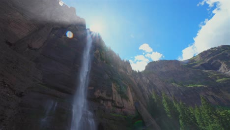 Sunny-mist-Telluride-Bridal-Veil-Falls-Waterfall-Black-Bear-Pass-Road-Colorado-landscape-pan-down-motion-spray-Ouray-Ridgway-Box-Canyon-cliffside-hydropower-house-4wd-hiking-blue-sky-boulders-creek