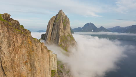 Drone-reveal-sharp-pointed-arctic-Segla-mountain-surrounded-by-fog-in-Norway