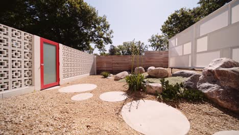 push-in-shot-of-a-modern-California-inspired-breeze-block-garden-with-a-red-door-on-the-side-of-a-luxury-home