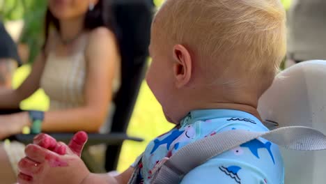 Happy-baby-eating-lunch-outdoors-on-summers-day-and-is-covered-in-food