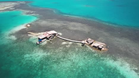 Isolated-stilt-house-over-turquoise-waters-in-Los-Roques,-Venezuela,-captured-in-an-aerial-view