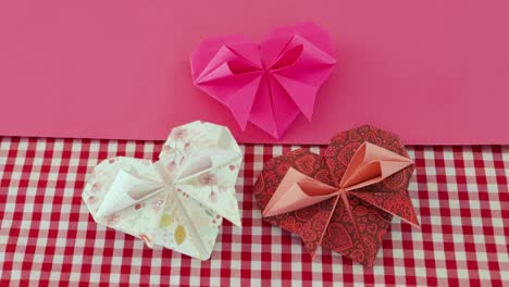 Folded-decorative-origami-paper-Valentine-hearts,-checkered-tablecloth