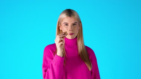 Attractive-Blonde-Woman-Eating-Wafer,-Colorful-Studio-Portrait