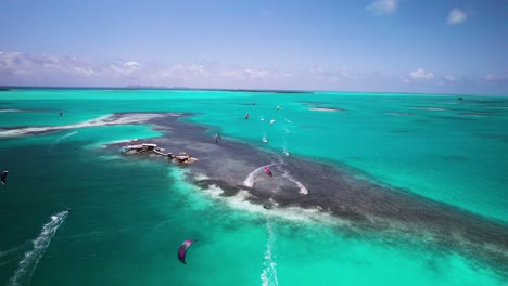 Los-Kitesurfistas-Se-Deslizan-Por-Las-Aguas-Turquesas-De-Los-Roques,-Capturados-Desde-Una-Perspectiva-Aérea