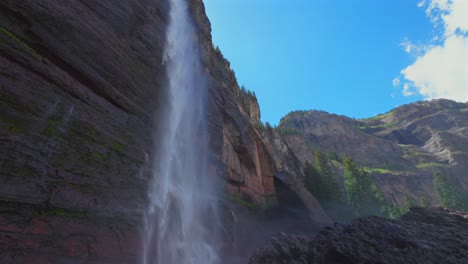 Mist-spray-Telluride-Bridal-Veil-Falls-Waterfall-Black-Bear-Pass-Road-Colorado-landscape-pan-down-slow-motion-Ouray-Ridgway-Box-Canyon-cliffside-hydropower-house-4wd-hiking-blue-sky-creek-windy