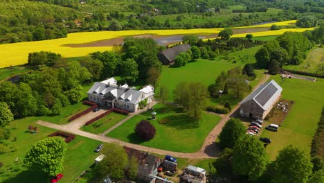 Vista-Aérea-De-La-Mansión-Babtyno,-Una-Finca-Histórica-Rodeada-De-Exuberante-Vegetación,-Con-Arquitectura-Clásica-Y-Un-Jardín-Bien-Cuidado.