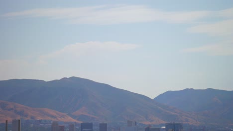 Wasatch-Mountain-Range-downtown-Salt-Lake-City-Airport-SLC-Utah-aerial-drone-USA-flag-summer-blue-sky-morning-afternoon-The-Great-Salt-Basin-Lake-County-region-LDS-highways-buildings-pan-down