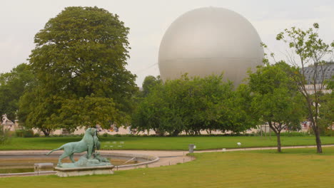 The-Olympic-cauldron-soars-in-a-hot-air-balloon-against-the-backdrop-of-Tuileries-Gardens,-showcasing-a-stunning-display-of-the-torch's-flame