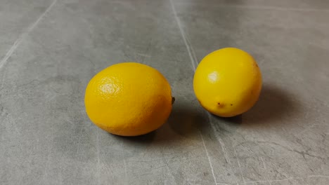 A-close-up-of-two-ripe-yellow-lemons-on-a-smooth-surface