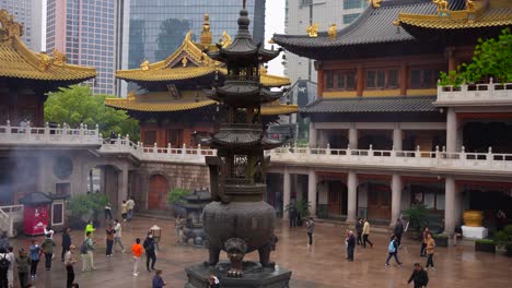 Jingan-Temple-golden-roofs-amid-Shanghai's-modern-skyline-outside-its-yard,-China