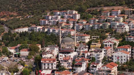 Aerial-telephoto-dolly-to-mosque-of-Kas,-Antalya,-Turkey,-featuring-the-scenic-town-with-red-tiled-roofs-and-white-walls