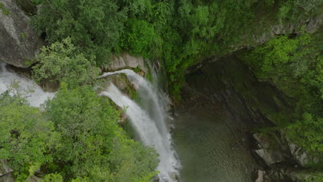 Drone-captures-the-top-view-of-a-majestic-waterfall-source-nestled-in-dense-forest-greenery