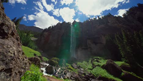 Summer-Telluride-Box-Canyon-Bridal-Veil-Falls-Waterfall-Colorado-landscape-pan-down-slowly-mist-spray-cliffside-Powerhouse-Hydroelectric-power-plant-Black-Bear-Pass-Board-sunny-blue-sky-clouds-scenery