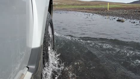 A-close-up-shot-of-a-car-driving-through-a-flooded-river-on-remote-mountain-roads-in-Iceland