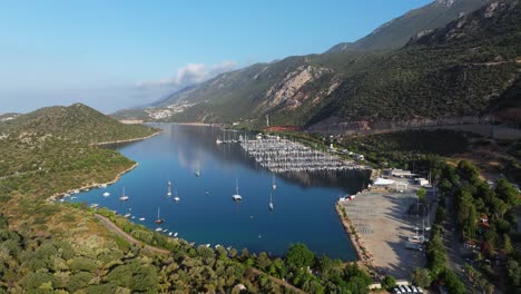 Aerial-dolly-of-Kas-marina-in-Antalya,-Turkey,-with-docked-boats-along-the-blue-Mediterranean-waters-and-scenic-coastal-hills