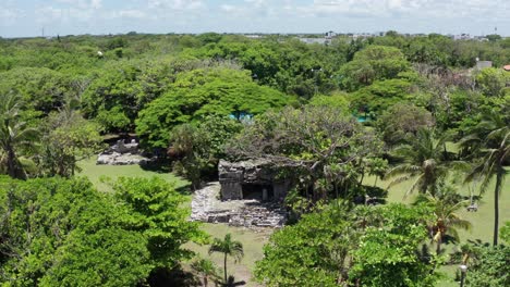 Low-close-up-aerial-shot-of-the-Xaman-Ha-Mayan-ruins-in-Playa-del-Carmen,-Mexico