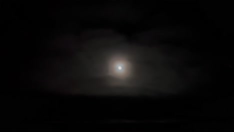 Aerial-footage-taken-from-a-jet-cockpit-of-the-full-moon-and-its-halo-while-flying-under-a-layer-of-clouds