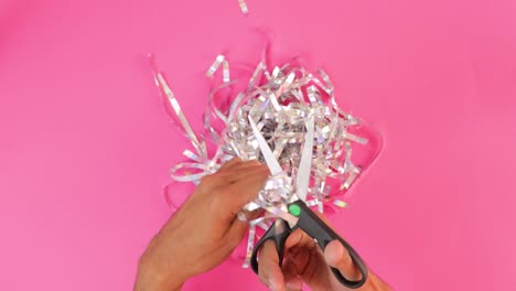 Cutting-iridescent-paper-strips-into-silver-confetti-with-scissors