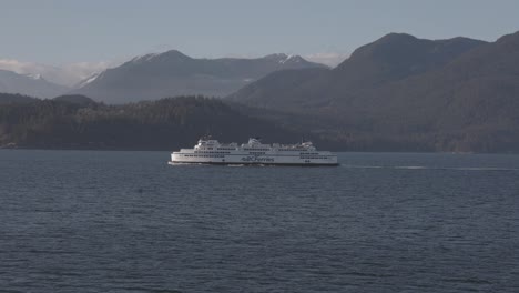 BC-ferry-boat-navigating-on-sea-water-with-mountains-in-background,-British-Columbia