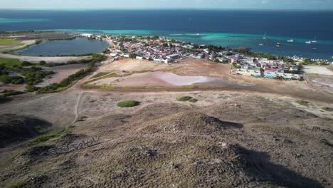 Gran-roque-village-with-lighthouse-in-the-foreground-and-the-sea-in-the-background,-aerial-view