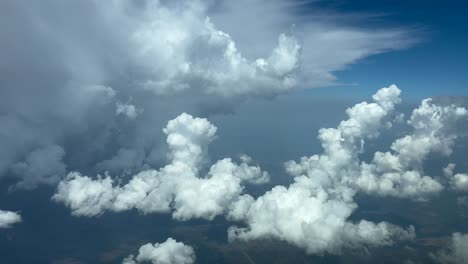 Pilot’s-POV-FPV-flying-through-a-blue-sky-with-a-huge-storm-cumulonimbus-cloud-on-the-left-hand-side-and-some-cottony-clouds-ahead-and-bellow